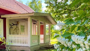 Une petite maison de plain-pied avec un porche, une lampe et une sculpture d’oiseau.