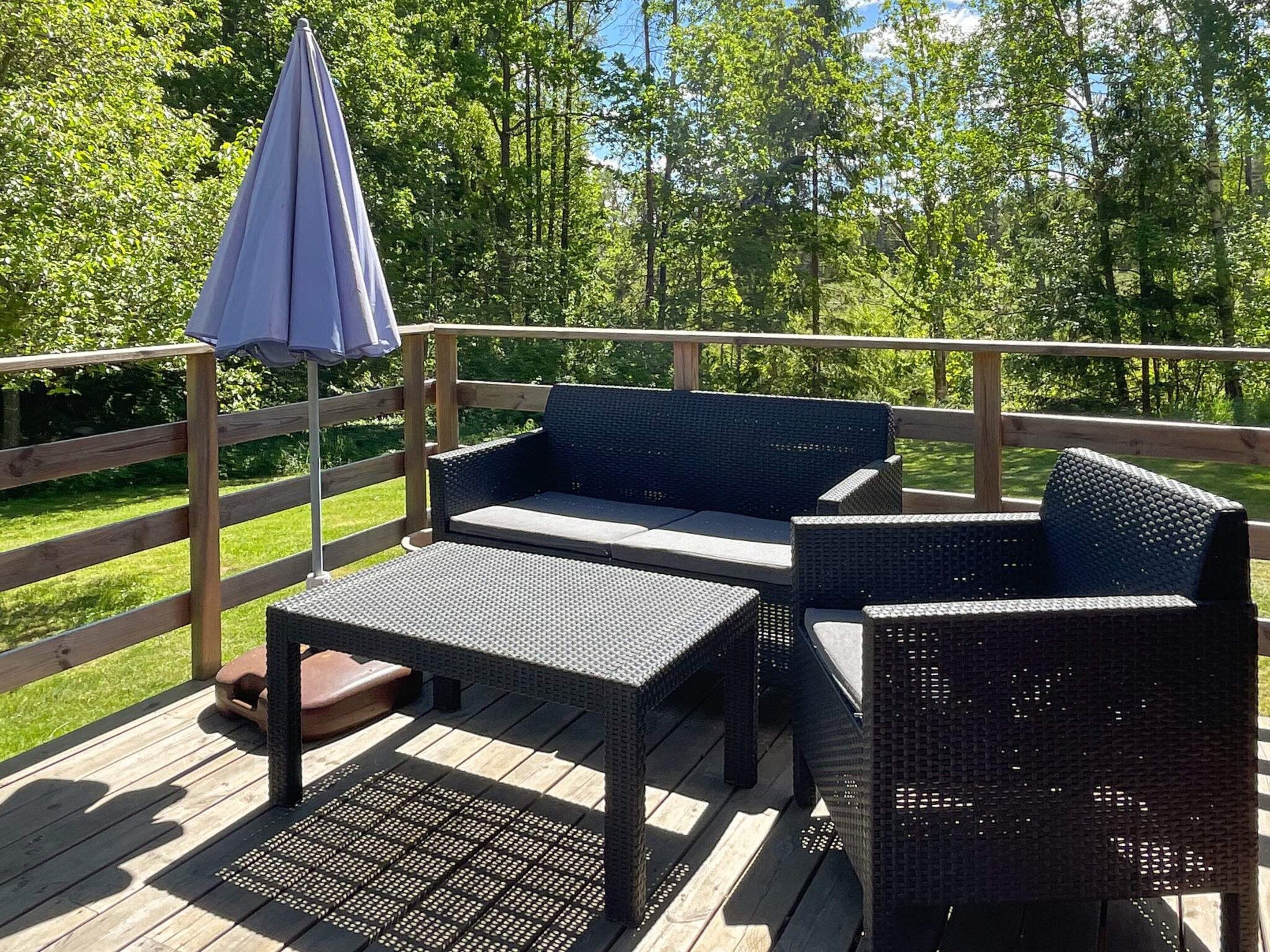 Une terrasse dotée de meubles en osier, notamment d’un canapé et de deux fauteuils, ainsi que d’une petite table.