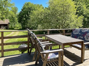 A wooden deck with a table and chairs, a grill, and a view of a grassy area and trees. - 5 Person Holiday Home in Ruda (Ruda)