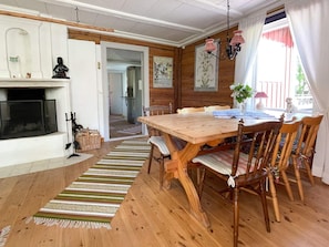 A wooden dining table with chairs, a fireplace, and a kitchen in the background. - 5 Person Holiday Home in Ruda (Ruda)
