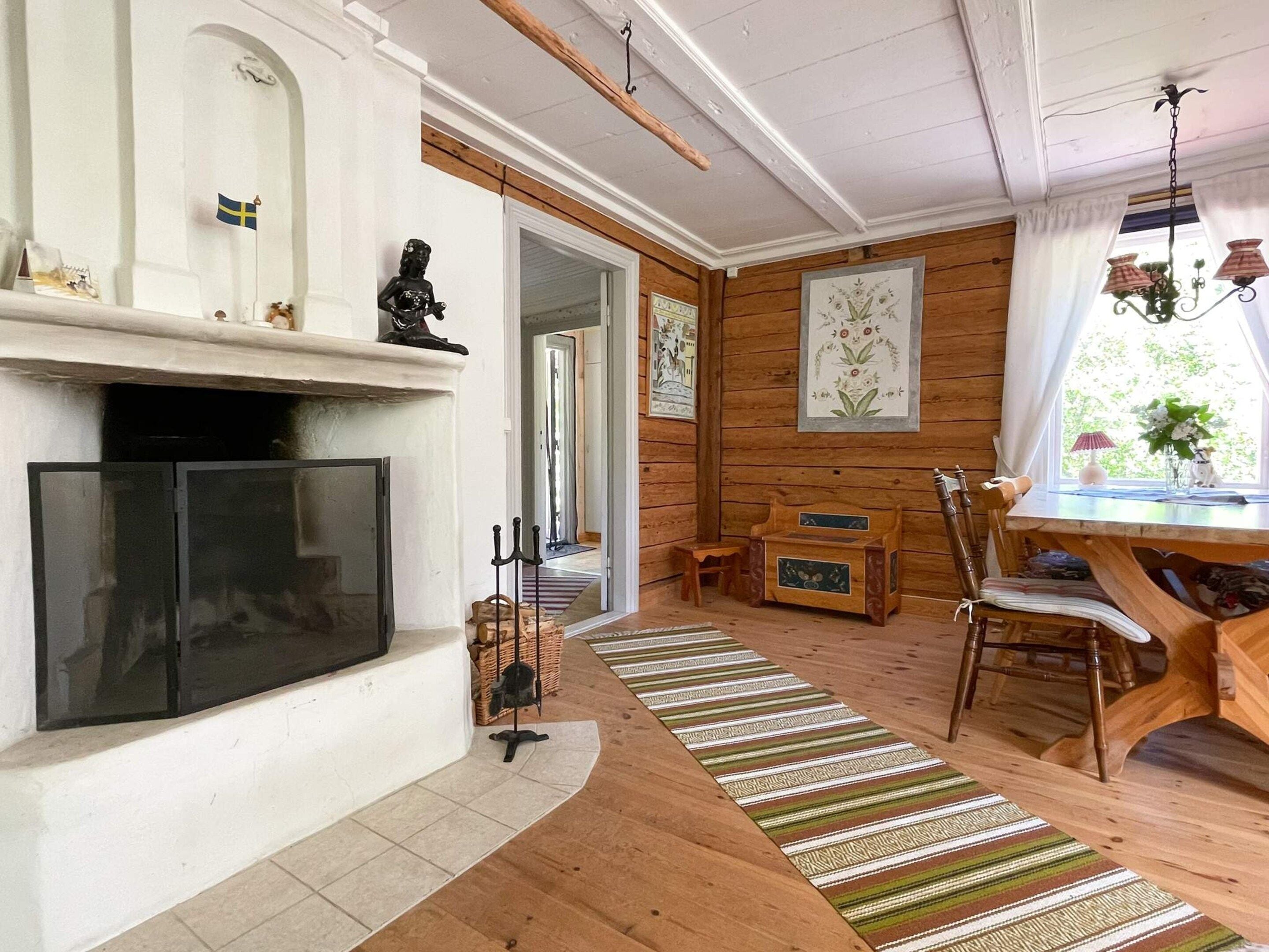Een gezellige woonkamer met een open haard, houten meubels en uitzicht op een andere kamer.