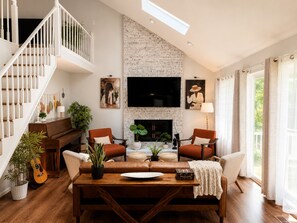 Ein geräumiges Wohnzimmer mit Kamin, Treppe und großem Fenster.