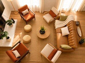 Ein Wohnzimmer mit einem braunen Ledersofa, zwei Sesseln, einem Couchtisch und einer Stehlampe.