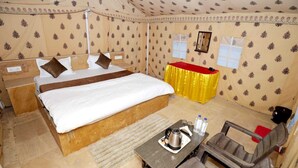 A tent-style room with a bed, a small table with a kettle, and a chair. - Mehta Desert Camp (Jaisalmer)