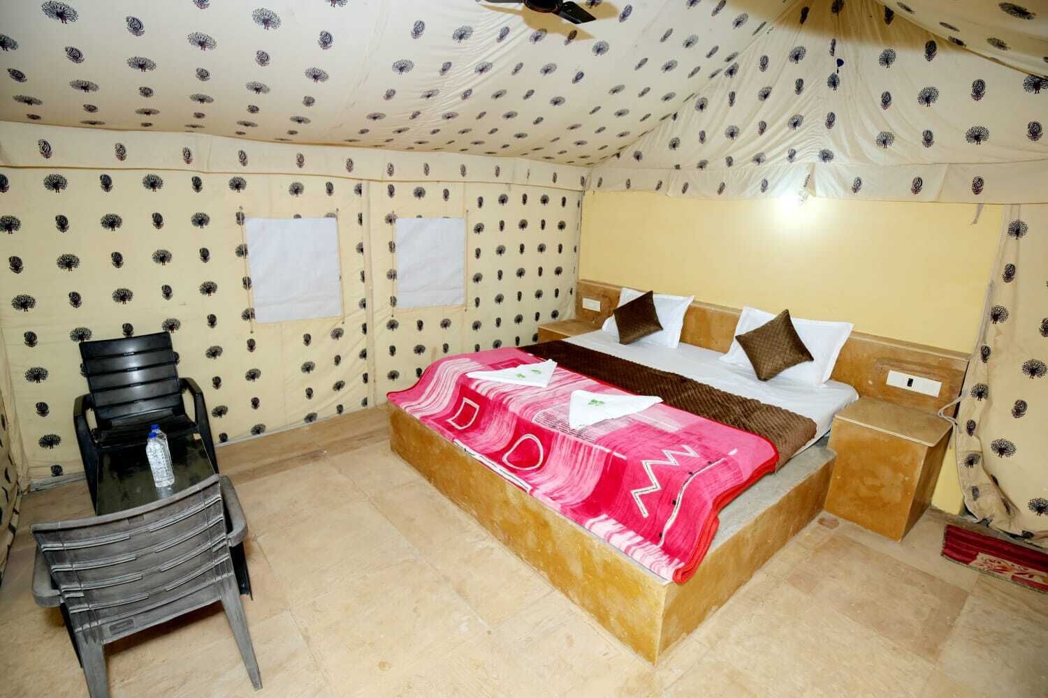 Quarto com cama, cadeira, mesa de cabeceira e parede com desenho estampado.