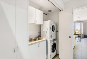 A compact laundry area with a washing machine, a sink, and a door leading to a balcony.