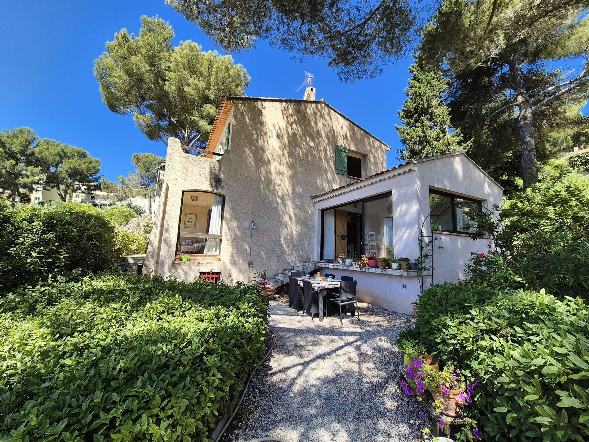A house with a gravel pathway leading to a patio area with a table and chairs.