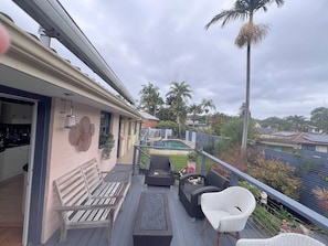 Eine Terrasse mit Gartenmöbeln, einem Pool und Blick auf Palmen und Häuser.