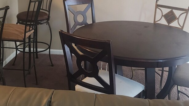 A dining area with a round table, four chairs, and a hanging light fixture.