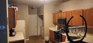 Una cocina con armarios de madera, microondas, horno y cafetera.