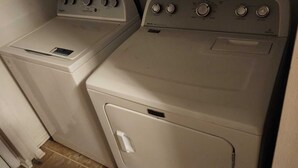 A laundry area with two washing machines and a dryer.