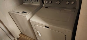 A laundry area with two washing machines and a dryer.