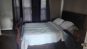 A bed with a headboard, a bedside table, and a door.