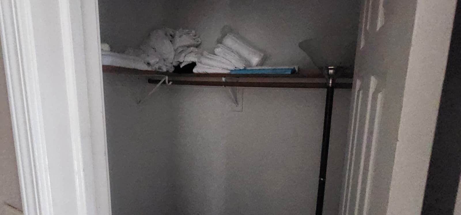 A room with a door frame, a shelf with folded items, and a wall.