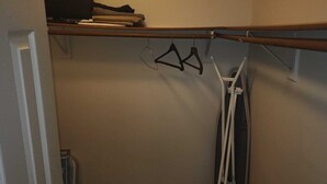 A closet with hanging clothes and a clothes rack.