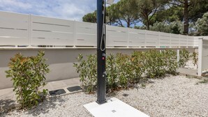 Eine Solaranlage mit einem Steuerungskasten, umgeben von Kies und kleinen Sträuchern, vor dem Hintergrund eines weißen Zauns und Bäumen.