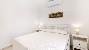 Ein Schlafzimmer mit einem Bett, Nachttischen, einer Klimaanlage und einem Wandbild.