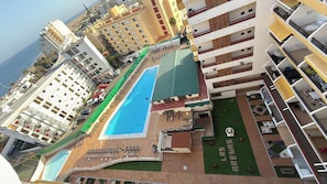 Ein mehrstöckiges Hotel mit Swimmingpool, Außenbereich und angelegtem Garten.