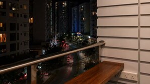 A balcony with a view of a cityscape at night, including buildings and a river.