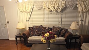 A living room with a sofa, a coffee table with a vase of flowers, and two lamps on side tables.