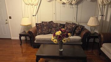 A living room with a sofa, a coffee table with a vase of flowers, and two lamps on side tables.