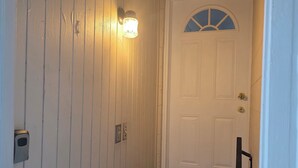 A staircase with a handrail, a white door with a window, and a wall-mounted light fixture.
