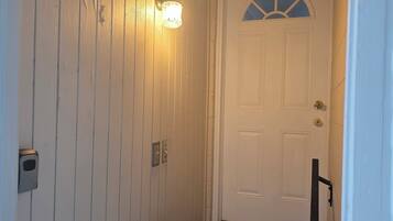 A staircase with a handrail, a white door with a window, and a wall-mounted light fixture.