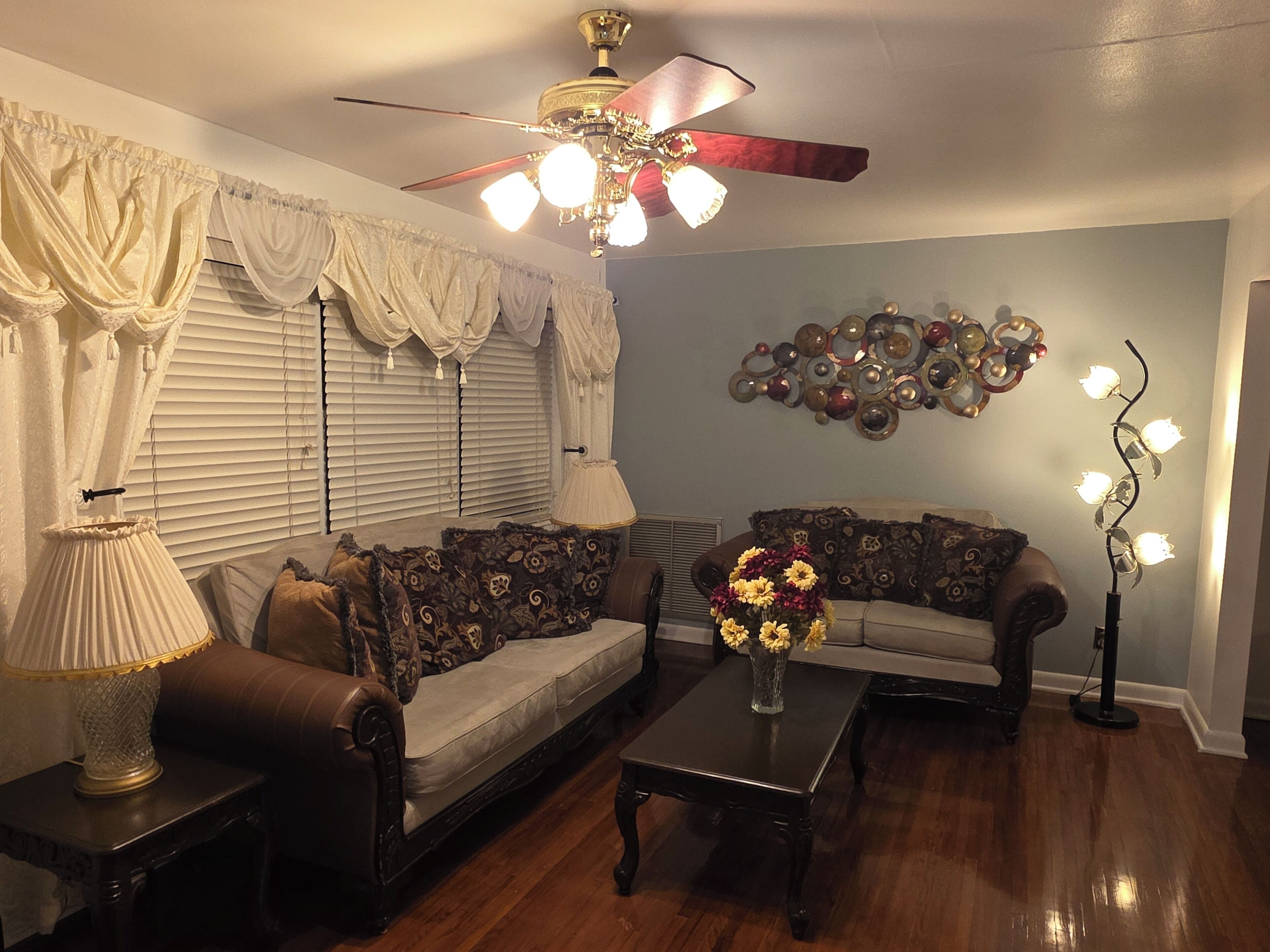 A living room with a ceiling fan, two sofas, a coffee table, and a decorative wall piece.