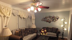 A living room with a ceiling fan, two sofas, a coffee table, and a decorative wall piece.