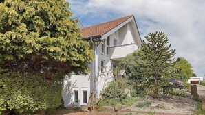 A two-story house with a sloped roof, a front door, and a visible garage.