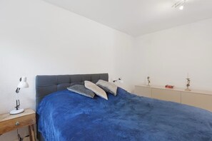 A bedroom with a bed, bedside lamps, a nightstand, a dresser, and a small decorative item on the dresser.
