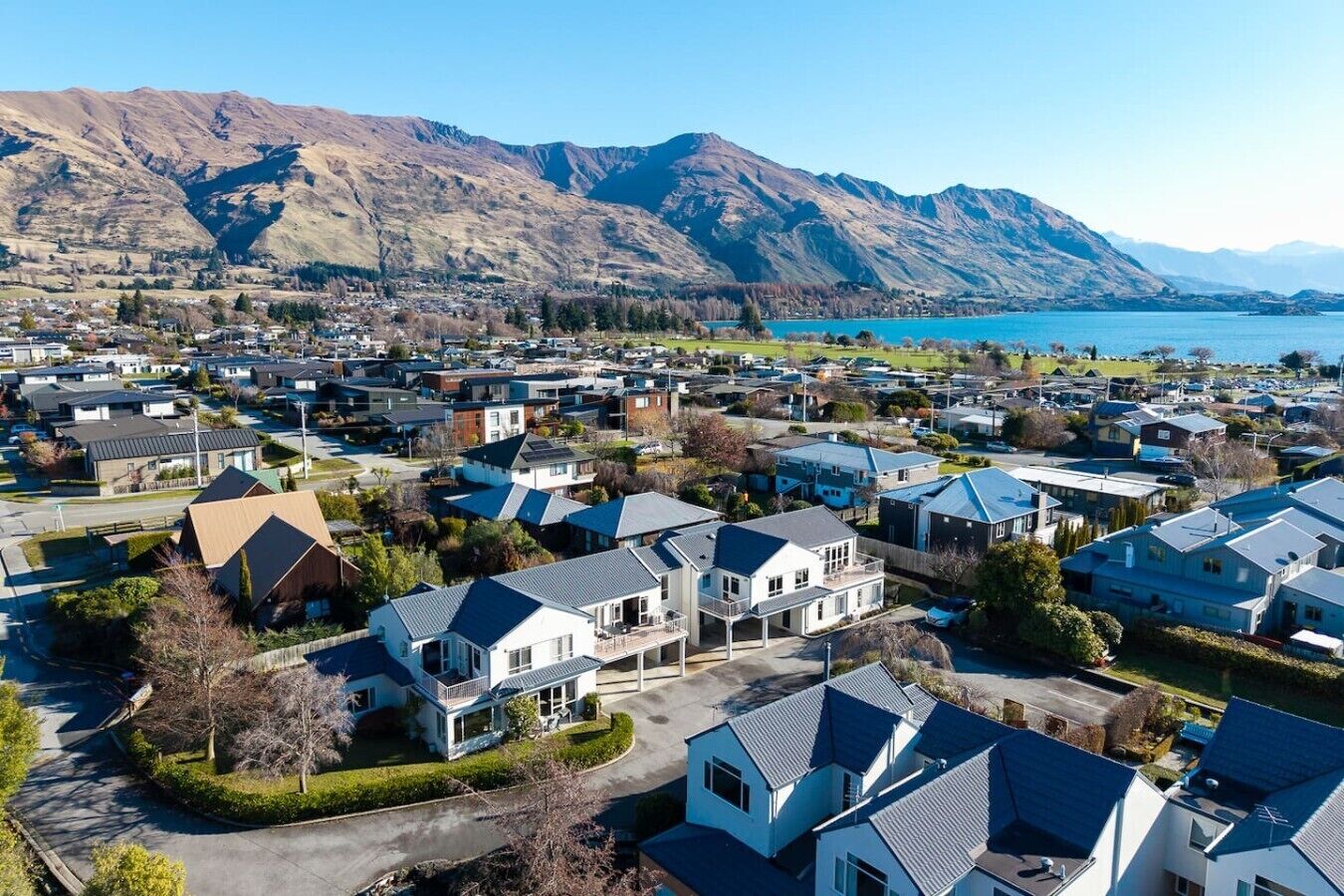 A residential area with houses, a road, and mountains in the background.