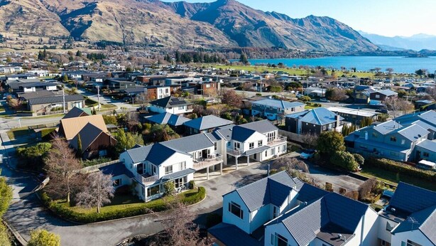 A residential area with houses, a road, and mountains in the background. - Central Wanaka 3BR Apartment – Walk to Lake & Town (Wānaka)