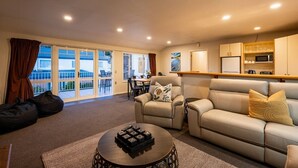 A living room with a sofa, armchairs, a coffee table, and a balcony with a view. - Central Wanaka 3BR Apartment – Walk to Lake & Town (Wānaka)