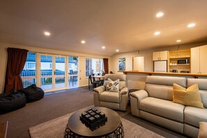 Un salón con sofá, sillones, una mesa de centro y un balcón con vistas.