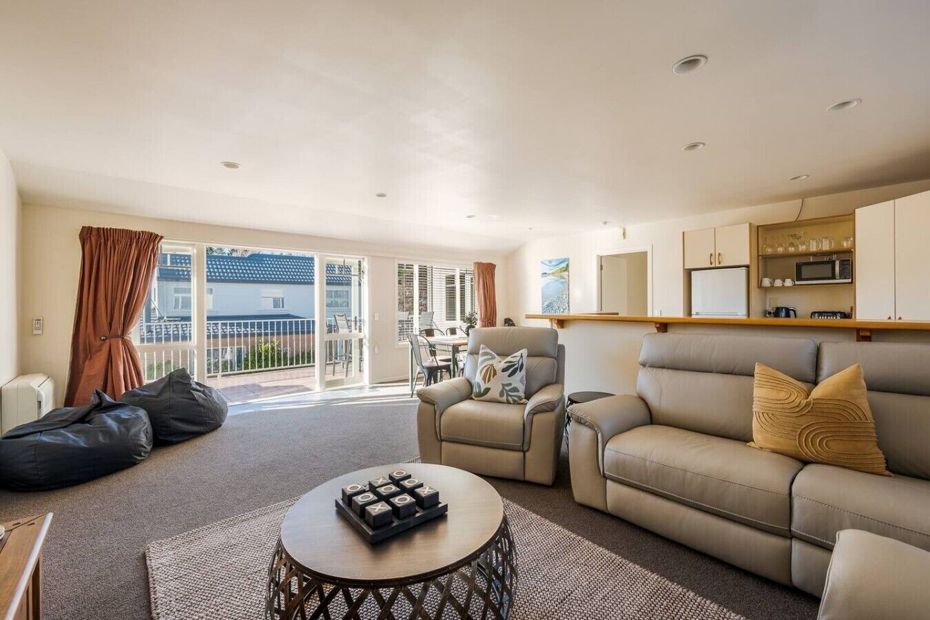 A living room with a sofa, armchairs, a coffee table, and a balcony with a view.