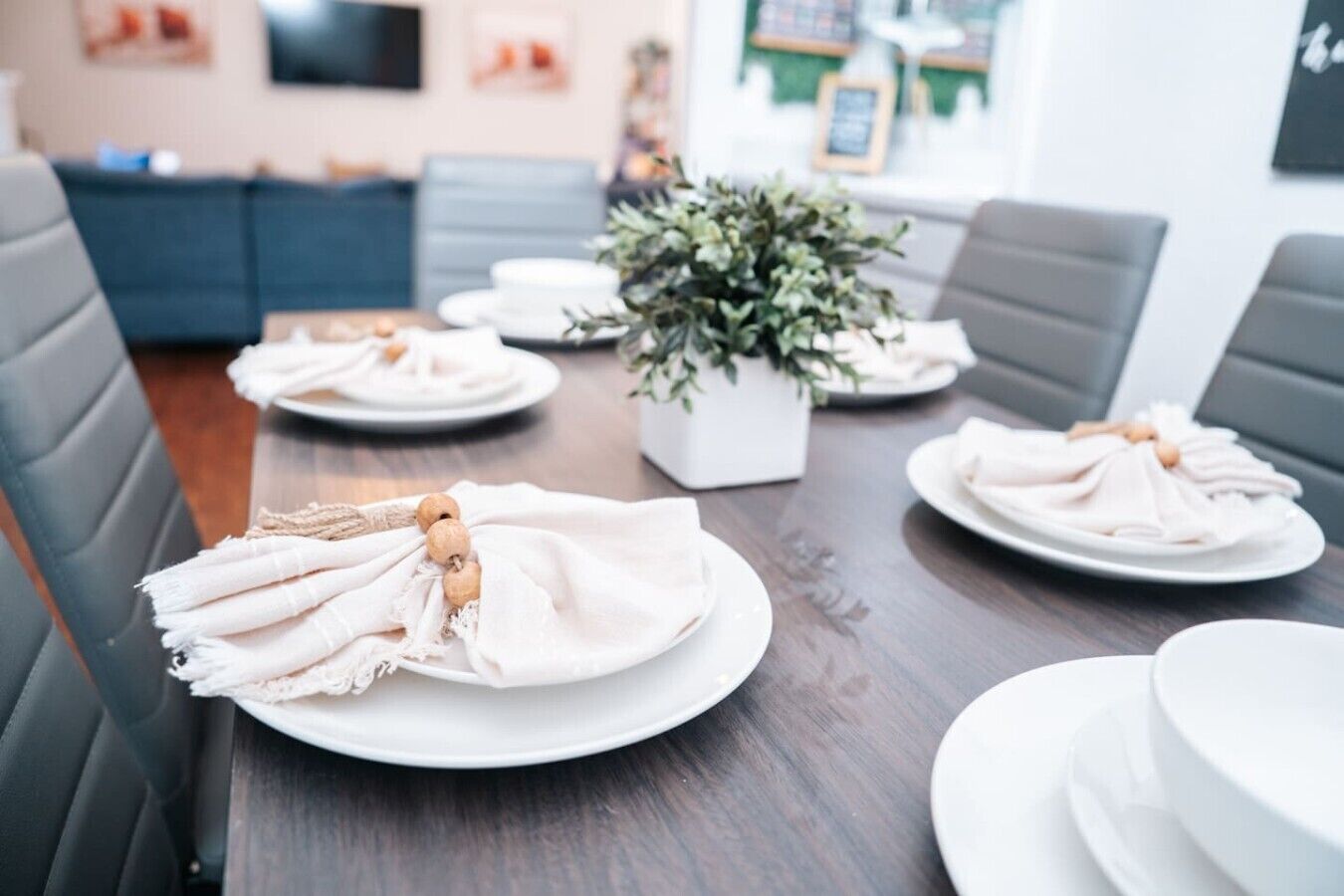 A dining table set with plates, napkins, and a centerpiece.
