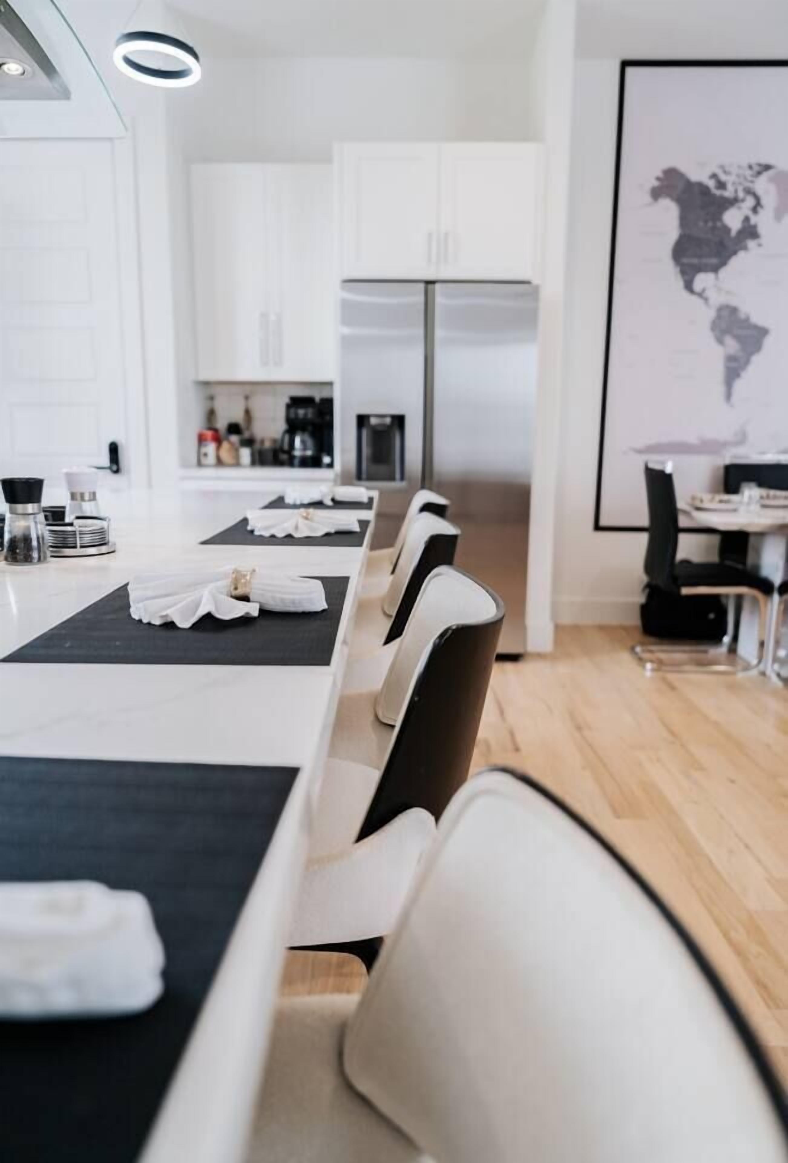 Una habitación de hotel moderna con zona de comedor, cocina y un mapa del mundo en la pared.