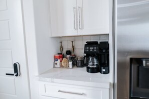 Eine Küche mit weißen Schränken, einer Marmorarbeitsplatte und Kaffeemaschinen.