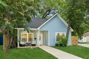 Una casa a un piano con un portico coperto, un piccolo patio e un garage.