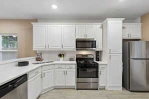 Una cucina moderna con mobili bianchi, elettrodomestici in acciaio inossidabile e lavastoviglie.