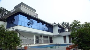 A modern building with a swimming pool, large windows, and a balcony.