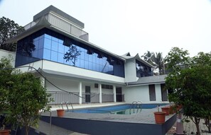 A modern building with a swimming pool, large windows, and a balcony.