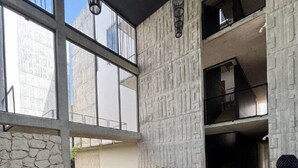 Un intérieur moderne avec un mur en pierre, un canapé foncé, des sièges ronds et un escalier.