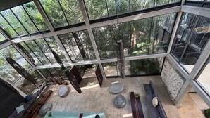 Un intérieur moderne avec un plafond en verre, une table centrale, des coins salon et un mur en pierre.