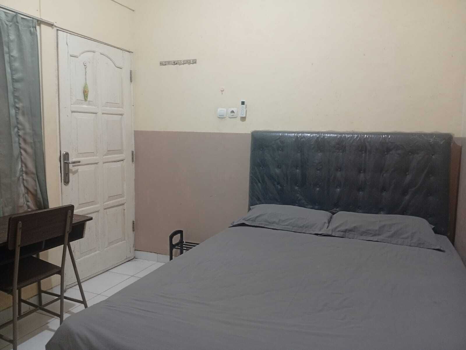 A bedroom with a bed, a desk, and a chair.