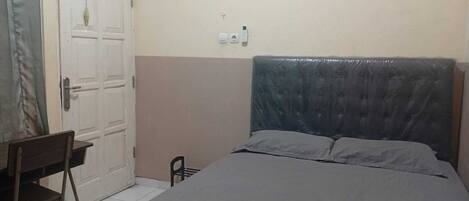 A bedroom with a bed, a desk, and a chair.