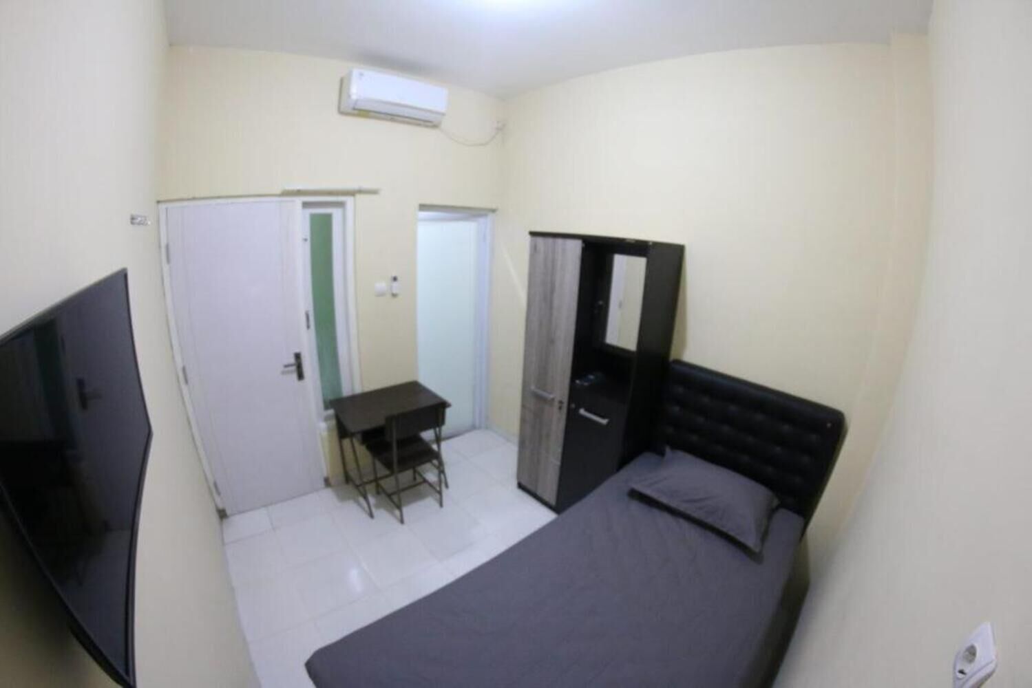 Une petite pièce comprenant un lit, un bureau, une armoire et un téléviseur.