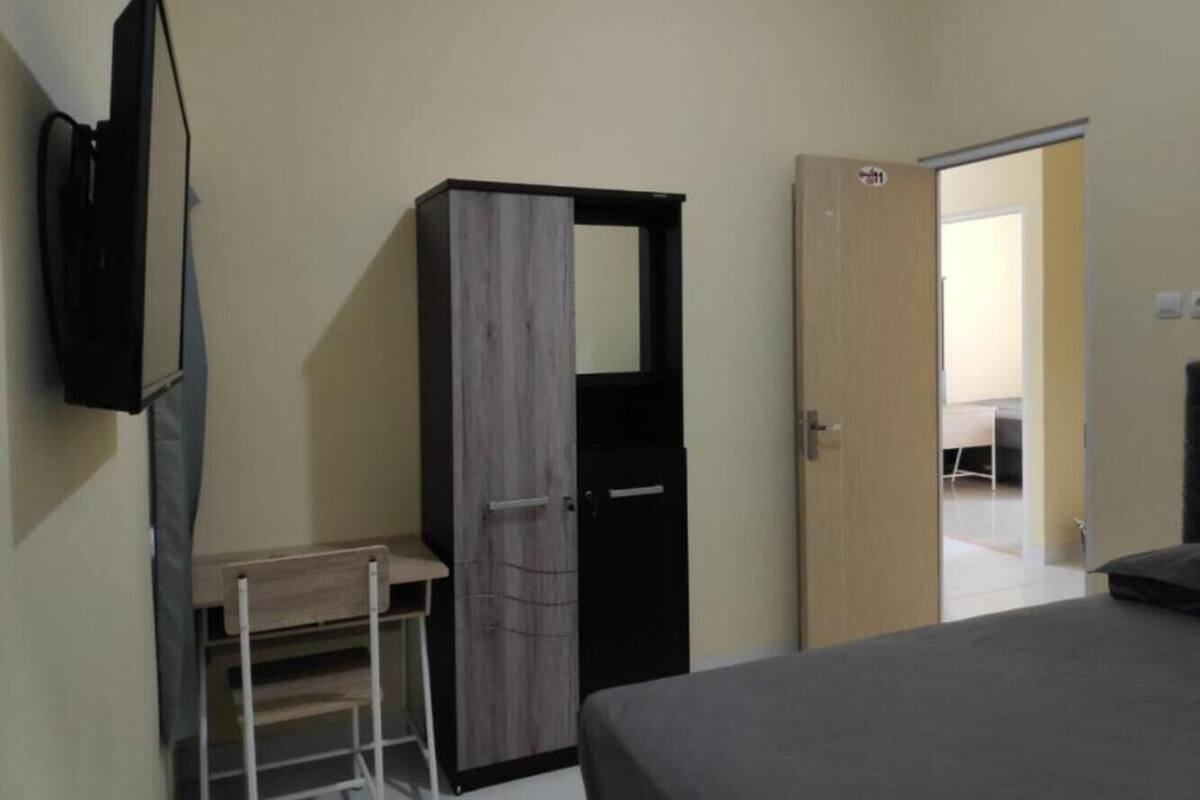 Een slaapkamer met een bed, een kledingkast, een bureau en een televisie.