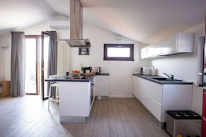 Eine moderne Küche mit weißen Schränken, einer zentralen Kochinsel, einem eingebauten Backofen und einem Fenster über der Spüle.